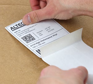 Geprint vinyl verzendlabel met adresgegevens, barcode en datamatrixcode wordt van de drager verwijderd